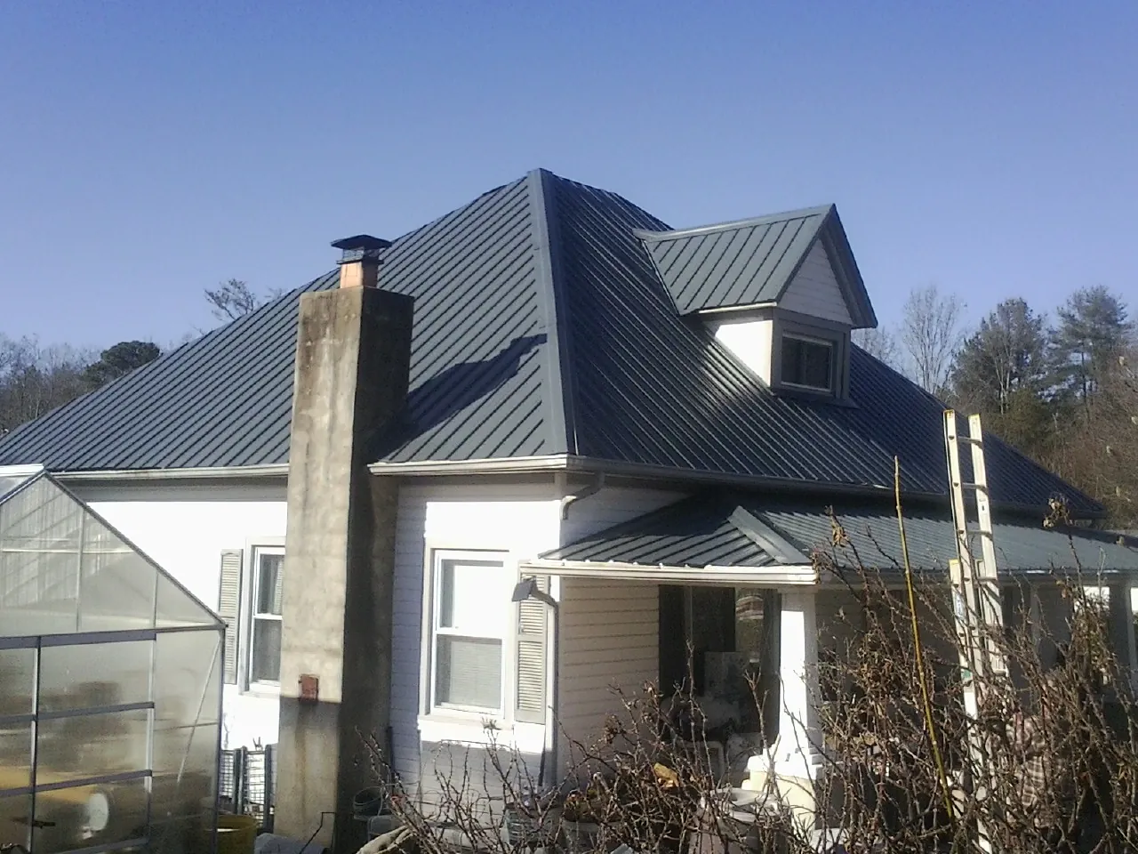Dark blue standing seam metal roof on a white farmhouse with dormer — Slate & Tile Roof Repair by Roofing Brothers in Mason