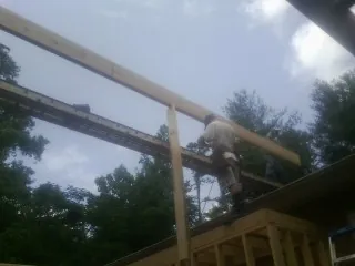 Carpenter setting a ridge beam over a new addition frame — Ice Dam Removal by Roofing Brothers in Mason
