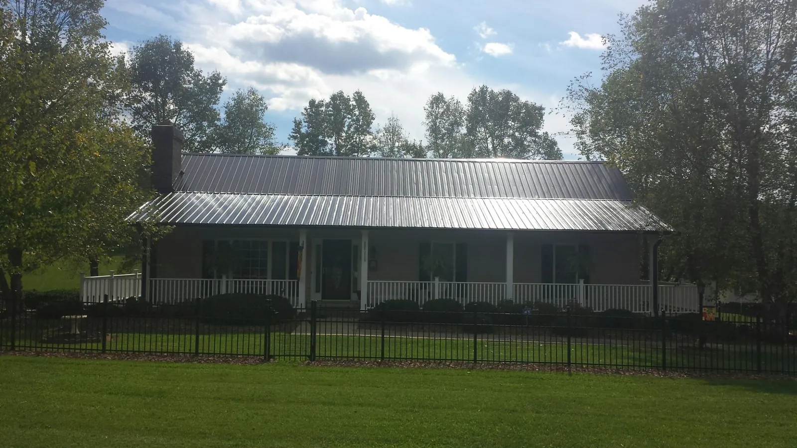 Gray metal roof on a brick ranch with a full width front porch — Gutter Guard Installation work by our crew in Mason